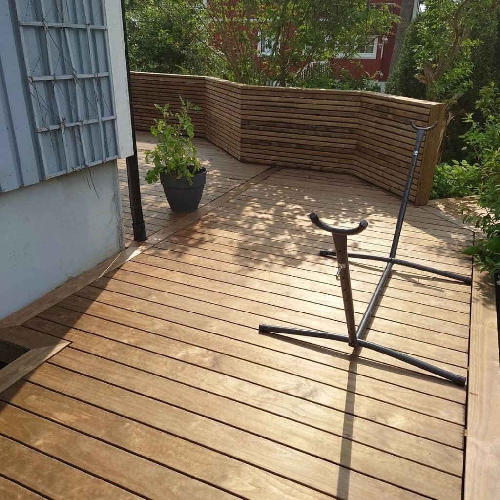 Træterrasse med plante og cykelstativ.