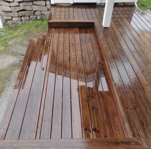 Nyvasket træterrasse med regndråber, klar til brug.