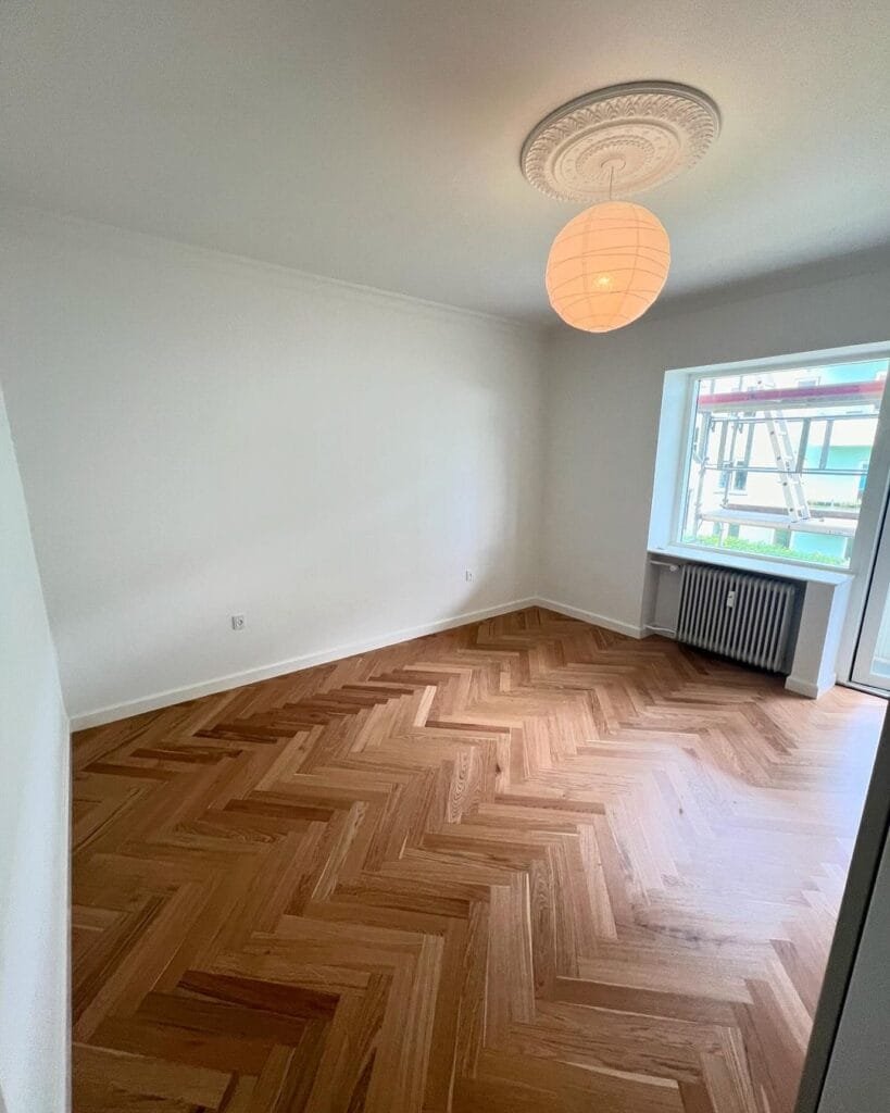 Tomt rum med sildebensparketgulv og papirlampe